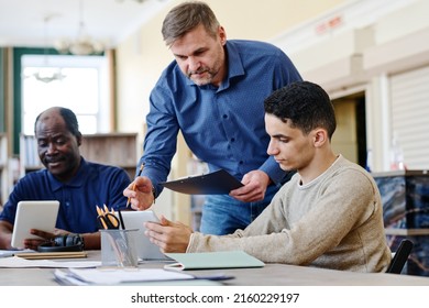 Mature Caucasian man working as English language teacher for immigrants explaining grammar rule to his student - Shutterstock ID 2160229197