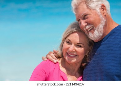 Mature Caucasian Senior Couple In Bright Clothes Carefree Outdoors By The Ocean On Tropical Luxury Bahamas Resort 