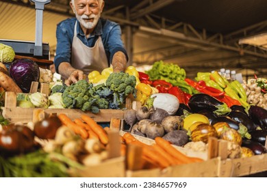 A mature Caucasian vegetable owner arranging vegetables at his stall getting ready for the day. - Powered by Shutterstock