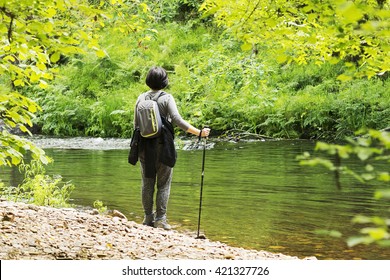 mature caucasian woman hiking , hike in the river ; traveler with backpack on beautiful landscape