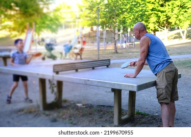 Mature Charismatic Sports Man, Senior 60 Years And His Rival, Child, Boy 8 Years Old At Tennis Table, Grandson And Grandfather Have Family Match Ping Pong, Joint Activity During Holidays