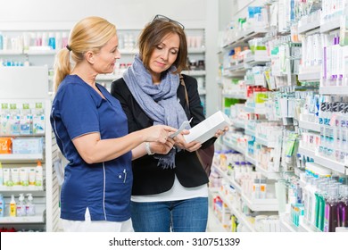 Mature Chemist Explaining Product Details To Female Customer In Pharmacy