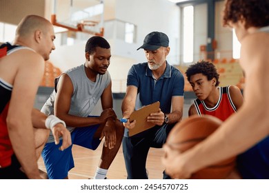 Mature coach giving instructions to his basketball team during sports training.  - Powered by Shutterstock