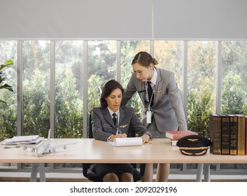 Mature Commercial Female Pilot Attentively Training Young Flight Crew. Beautiful Middle Aged Woman Plane Captain Flight Instructor Has Meeting Discussion With Aircrew Team. Aviation Business Concept.