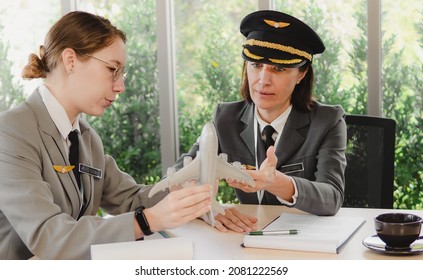 Mature Commercial Female Pilot Focus On Training Young Flight Crew. Beautiful Middle Aged Woman Airplane Captain Flight Instructor Has Meeting Discussion With Aircrew Team. Aviation Business Concept