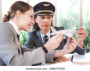 Mature Commercial Female Pilot Focused On Training Young Flight Crew. Beautiful Middle Aged Woman Airplane Captain Flight Instructor Has Meeting Discussion With Aircrew Team. Aviation Business Concept