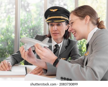 Mature Commercial Female Pilot Focused On Training Young Flight Crew. Beautiful Middle Aged Woman Airplane Captain Flight Instructor Has Meeting Discussion With Aircrew Team. Aviation Business Concept