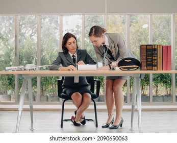 Mature Commercial Female Pilot Focused On Training Young Flight Crew. Beautiful Middle Aged Woman Airplane Captain Flight Instructor Has Meeting Discussion With Aircrew Team. Aviation Business Concept