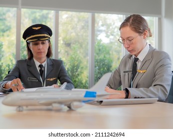 Mature Commercial Female Pilot Focused On Training Young Flight Crew. Beautiful Middle Aged Woman Airplane Captain Flight Instructor Has Meeting Discussion With Aircrew Team. Aviation Business Concept