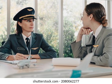 Mature Commercial Female Pilot Provides Training To Young Flight Crew. Beautiful Middle Aged Woman Airplane Captain Instructor Has A Meeting, Discussion With Aircrew Team. Aviation Business Background