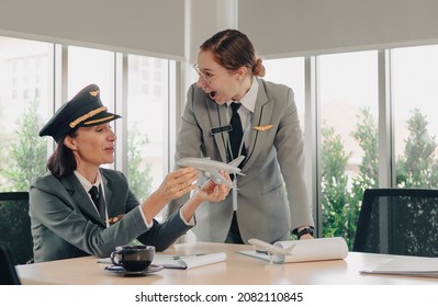 Mature Commercial Female Pilot Surprised Young Flight Crew During Training. Beautiful Middle Aged Woman Airplane Captain Flight Instructor Has Discussion With Aircrew Team. Aviation Business Concept