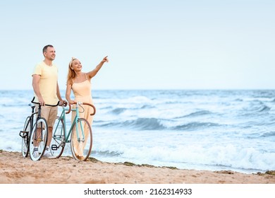 Mature couple with bicycles walking along sea beach on summer day - Powered by Shutterstock