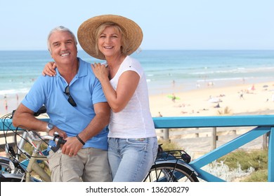 Mature couple with bikes by the beach