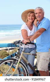 Mature Couple With Bikes By A Beach