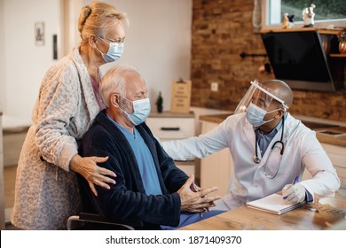 Mature couple and black doctor wearing protective face masks while talking at nursing home. - Shutterstock ID 1871409370