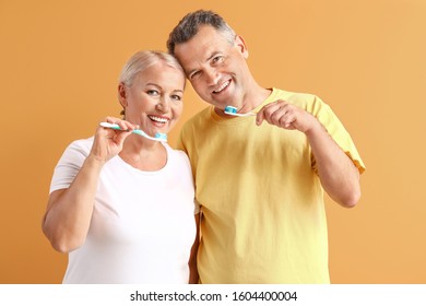 Mature Couple Brushing Teeth On Color Background