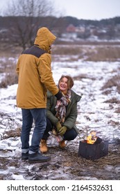 Mature Couple At Camp Fire, Happy Family On Winter Vacation. Away In Wild. Smiling Middle Aged Man And Woman In Snowy Nature Or Park Together. Family Seasonal Vacation Concept. 