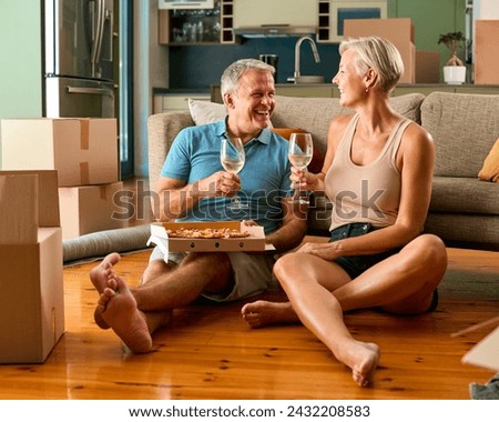 Mature Couple Celebrating In New Home On Moving Day Eating Pizza And Drinking Wine