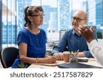 Mature couple consulting an adviser to explore retirement options, ensuring their life insurance and investments for the future. Meeting with financial broker about income and savings.