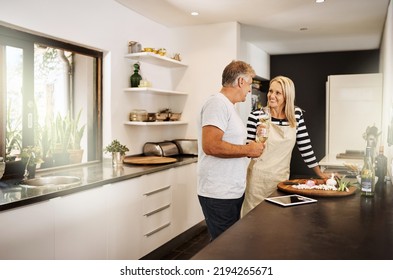 Mature Couple Cooking, Drinking Wine And Preparing A Meal Together While Bonding, Having Fun And Talking In Home Kitchen. Smiling, Happy And Caring Husband And Wife Making Healthy Food For Date