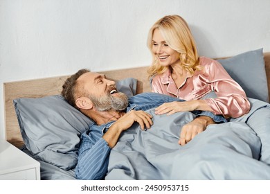 A mature couple in cozy homewear lying together in bed, sharing a quiet and loving moment. - Powered by Shutterstock