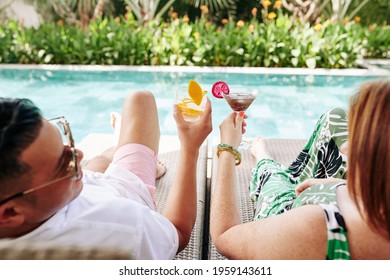 Mature couple with delicious cocktails relaxing on chaise-lounges by swimming pool of spa hotel - Powered by Shutterstock