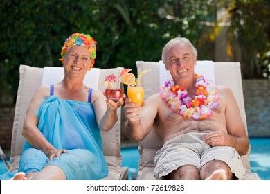 Mature couple drinking a cocktail  beside the swimming pool at home - Powered by Shutterstock