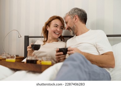 Mature couple enjoying coffee and breakfast in bed - Powered by Shutterstock