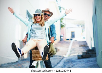 Mature couple enjoying while riding bicycle on street