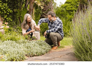 Mature couple gardening together, smiling and enjoying time in lush garden, outdoors. horticulture, outdoors, relaxation, lifestyle, nature, teamwork - Powered by Shutterstock