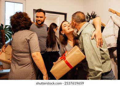 A mature couple greets their smiling guests at home. Laughing adult children came to their parents with gifts. Happy people spend family holidays together. Modern cozy home interior. - Powered by Shutterstock