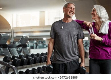 Mature couple, happy and bottle in gym, support and dumbbell for training, conversation and exercise. Man, woman and smile together for talking, workout and motivation with water at wellness club - Powered by Shutterstock