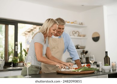 Mature couple, happy and cooking in kitchen for vegetable nutrition, vegan cuisine and diet for health. Smile, man and woman with food to prepare lunch, bonding together and white wine glass in home - Powered by Shutterstock