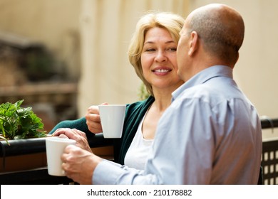 Mature couple having morning coffee at balcony and smiling - Powered by Shutterstock