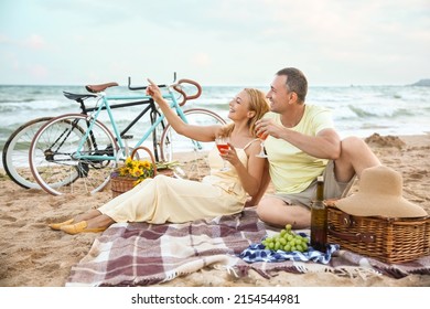 Mature couple having picnic near sea on summer day - Powered by Shutterstock