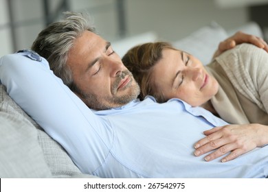 Mature Couple Having A Rest Laying Down In Sofa