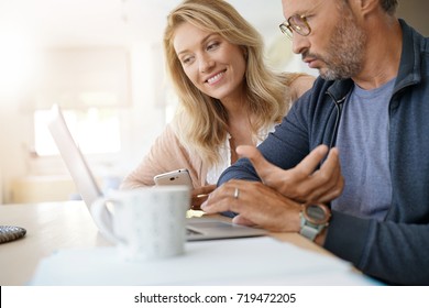 Mature Couple At Home Working On Laptop Computer