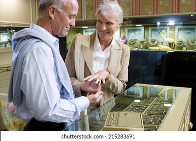 Mature couple in jewelery shop, woman trying on ring, smiling - Powered by Shutterstock