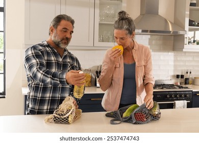 Mature couple in kitchen unpacking groceries, smelling fresh produce together, at home. Shopping, pantry, healthy, vegetables, culinary, togetherness - Powered by Shutterstock