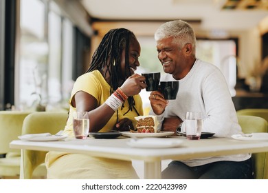 Mature couple laughing cheerfully while eating together in a coffee shop. Carefree senior couple having a good time in a restaurant. Happy mature couple enjoying their retirement together. - Powered by Shutterstock