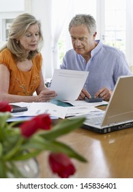 Mature Couple Looking At Bills With Calculator And Laptop