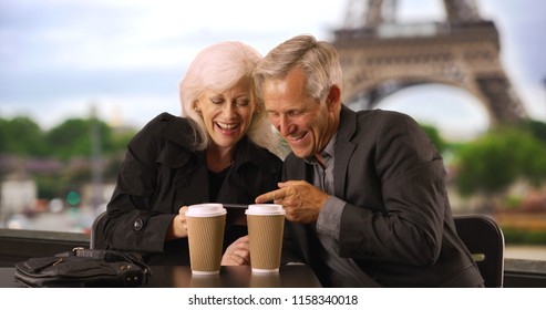 Mature Couple Looking At Smartphone Pictures In Paris