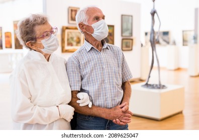 Mature Couple In Mask Protecting Against Covid Examines Paintings On Display In Hall Of Art Museum