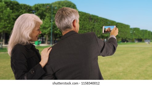 Mature Couple In Paris Looking At Picture On Their Smartphone