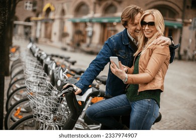 Mature couple picking up bicycles from the public bicycle sharing station in the city - Powered by Shutterstock