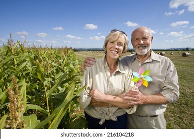 Mature couple with pinwheel by corn field, smiling, portrait - Powered by Shutterstock