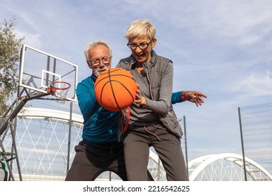 Mature Couple Play Basket Ball On Playground