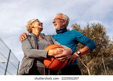 Mature Couple Play Basket Ball On Playground