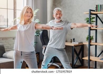 Mature couple practicing yoga and performing warrior yoga pose together - Powered by Shutterstock