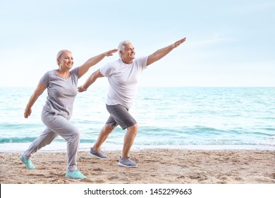 Mature couple practicing yoga at sea resort - Powered by Shutterstock